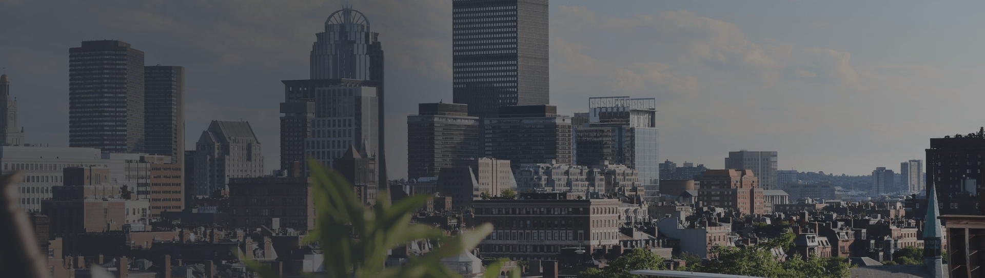 Boston city skyline featuring modern and historic buildings, with greenery in the foreground, representing relocation options for potential movers.