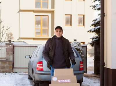 Man transporting fragile boxes in snowy driveway, showcasing Octopus Moving's professional moving services in Brookline, Massachusetts.