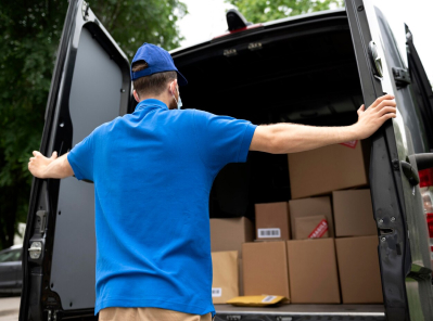 Delivery person in blue uniform loading boxes into moving van, representing Octopus Moving Company's reliable moving services in Belmont, MA.