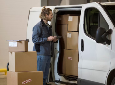 Man in a blue jacket loading boxes labeled "EXPRESS" into a moving van, representing Octopus Moving's efficient packing and delivery services.